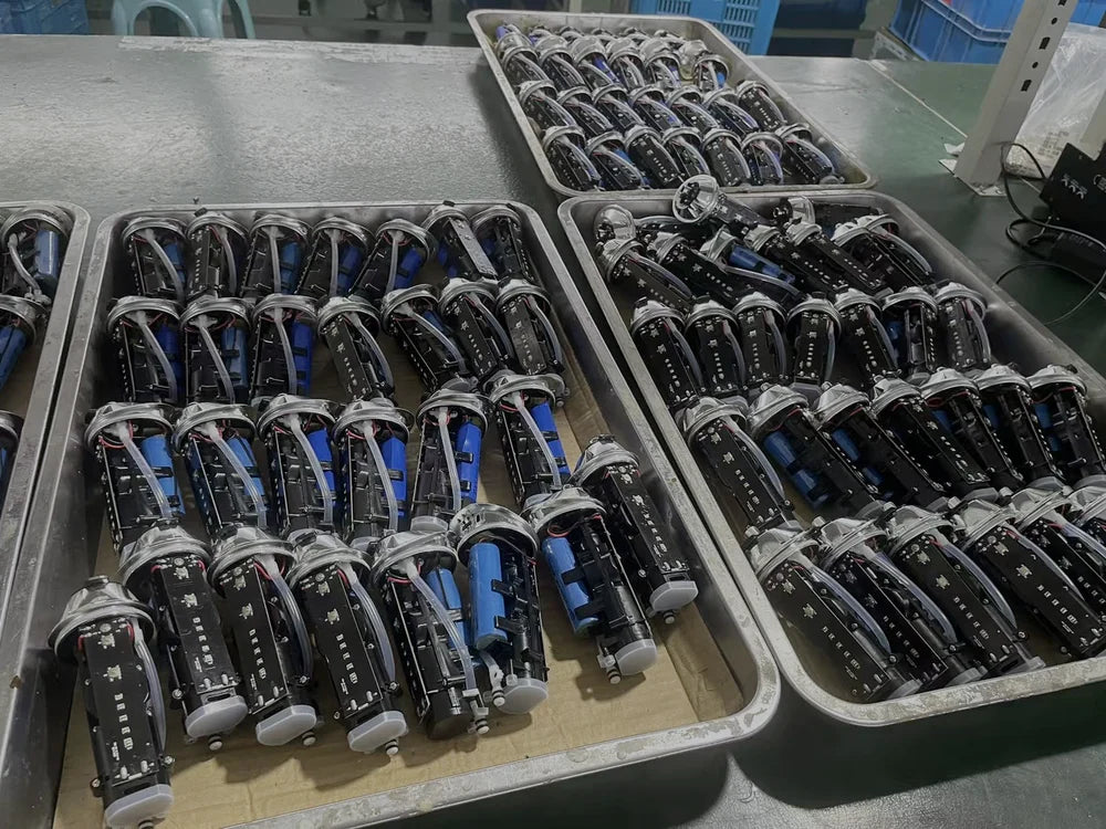 Trays of toothbrush sub-assemblies on a workbench: circuit boards, cells and motors before final assembly